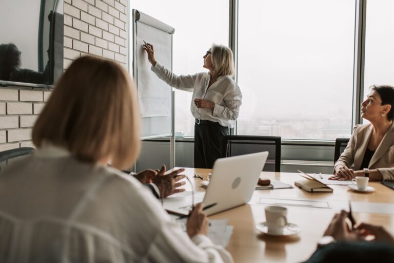 Mulher apresenta indicadores em flipchart durante reunião de equipe comercial em escritório